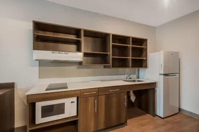 a kitchen with wooden cabinets and a white refrigerator at WoodSpring Suites Bellflower - Los Angeles in Bellflower