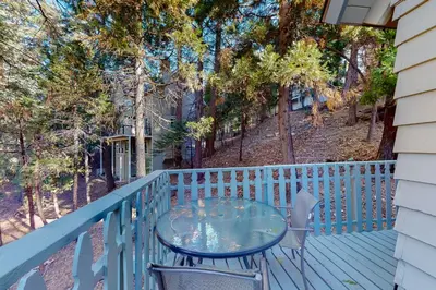 a table and chairs on a deck with trees at The Retreat on Wabash Lane in Lake Arrowhead