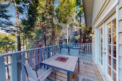 a blue porch with a table and chairs and trees at The Retreat on Wabash Lane in Lake Arrowhead
