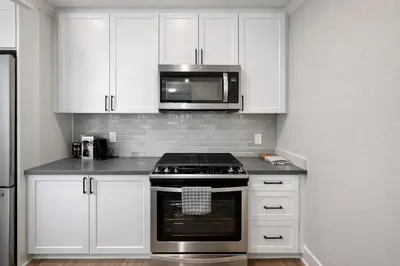 a kitchen with white cabinets and a stove and microwave at Luxury 2 Bedrooms 2 Bathrooms With Pool and Gym in Los Angeles
