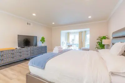 a white bedroom with a large bed and a flat screen tv at Single Level House with view and pool in Glendora