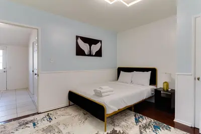 a white bedroom with a bed and a bathroom at 5 Bedroom Charmer with Pool in Reseda