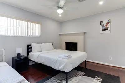 a white bedroom with two beds and a fireplace at 5 Bedroom Charmer with Pool in Reseda
