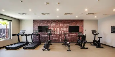 a gym with several treadmills and a brick wall at Ayres Hotel Rialto Fontana in Rialto