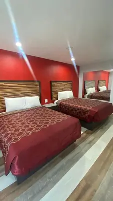 two beds in a hotel room with red walls at Plaza Inn Motel - Los Angeles area in Rosemead