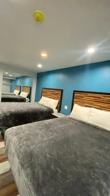 a bedroom with two beds and a blue wall at Plaza Inn Motel - Los Angeles area in Rosemead