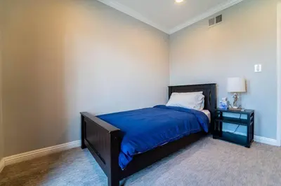 a bedroom with a bed with a blue blanket and a nightstand at Private Pool Oasis/Disney 15mins /Disney+ HBO/Gym in Placentia