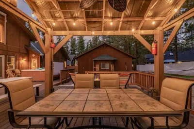 a wooden deck with a wooden table and chairs at A Snowmass Haven - EV, Sauna, Hot Tub - Walk to Slopes/lake in Big Bear Lake