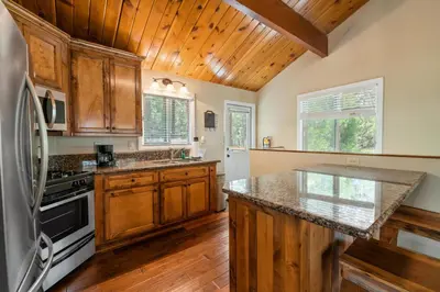 a kitchen with wooden cabinets and a refrigerator at Lakeview Trout N About - Walk to Lake, Close to Village & Slopes in Big Bear Lake