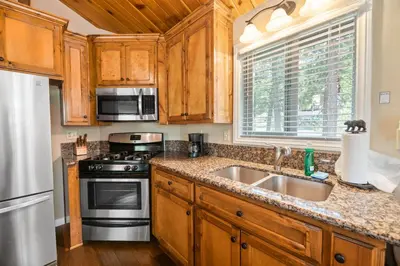 a kitchen with wooden cabinets and a stove and a sink at Lakeview Trout N About - Walk to Lake, Close to Village & Slopes in Big Bear Lake