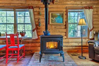 a fireplace in a room with a table and chairs at Pine Mountain Club Log Home with Deck and Grill! in Pine Mountain Club