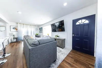 a living room with a gray couch and a blue door at Luxury Villa with Hot Tub! Minutes to Beach & Bars in Long Beach