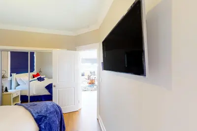 a bedroom with a large flat screen tv on a wall at Gull Cottage in Seal Beach