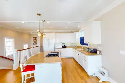 a kitchen with white cabinets and a large island at Gull Cottage in Seal Beach