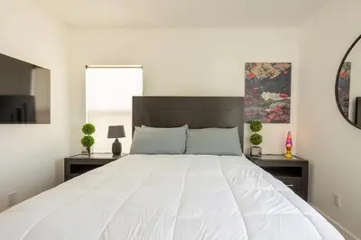a large white bed in a bedroom with a mirror at Coziest 1BD Bungalow 8min from airport, 4 min SoFi in Los Angeles