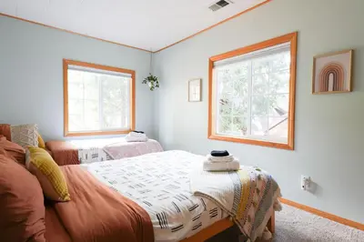 a bedroom with a bed and two windows at Aery Pines in Wrightwood