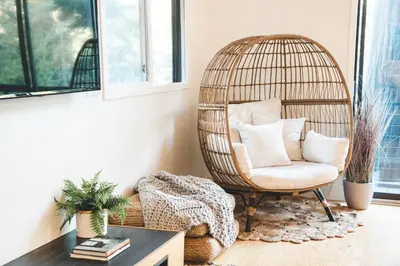 a rattan chair in a living room with a table at Modern Treetop Cabin by Lake Arrowhead Village in Lake Arrowhead