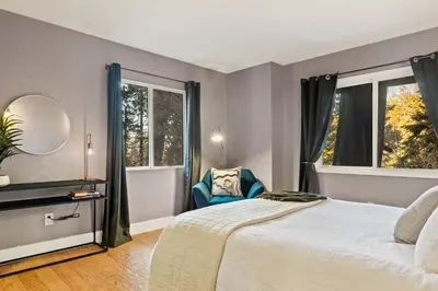 a bedroom with a bed and two windows at Modern Treetop Cabin by Lake Arrowhead Village in Lake Arrowhead