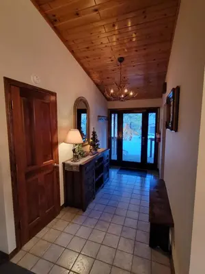 a hallway with a wooden ceiling and a table at Four Seasons Getaway-Private Hot Spa with Pine Tree Views-Walk to Village and Pineknot Trailhead-Plus King Bed! in Big Bear Lake