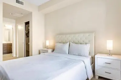 a white bedroom with a large bed and two lamps at Luxury 2 Bedroom 2 Bathroom With Fitness Center and Pool in Los Angeles