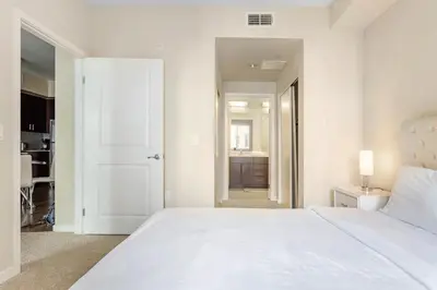 a white bedroom with a large bed and a bathroom at Luxury 2 Bedroom 2 Bathroom With Fitness Center and Pool in Los Angeles