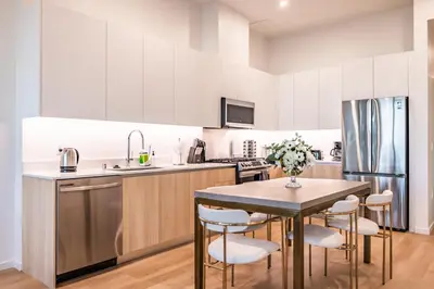 a kitchen with white cabinets and a table and chairs at @ Marbella Lane - Aesthetic 2BR w/Ocean views in Long Beach