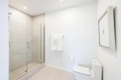 a white bathroom with a shower and a toilet at @ Marbella Lane - Luxury Beachside 2BR in Long Beach