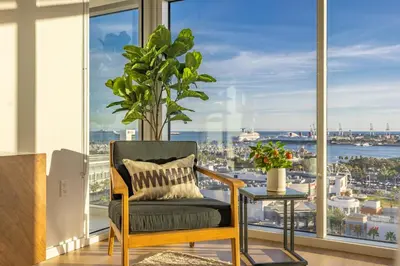a chair in front of a window with a plant at @ Marbella Lane - Penthouse w/ City & Ocean Views in Long Beach