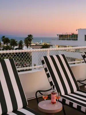 two chairs and a table with wine glasses on a balcony at The Eden in Los Angeles