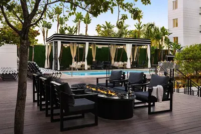 a patio with chairs and a fireplace next to a pool at The Eden in Los Angeles