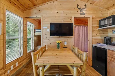 a dining room with a wooden table and a tv at Adorable little cabin #21 in Kernville