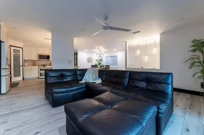 a living room with a leather couch and a kitchen at Modern San Pedro Home, Sleeps 12, Hot Tub, Fire Place, Private Parking in San Pedro