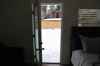 a bedroom with a door open to a snow covered yard at The Blue Lake Cabin! 1 min Walk to SnowPlay! in Big Bear City