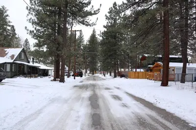 a snow covered street in a town with trees at The Blue Lake Cabin! 1 min Walk to SnowPlay! in Big Bear City