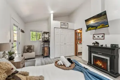 a living room with a fireplace and a bed at The RobinHood Retreat! A 1 min Walk to SnowPlay! in Big Bear City