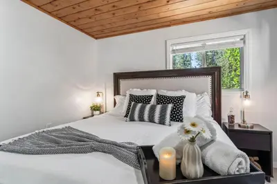 a bedroom with a large white bed with two candles at The RobinHood Retreat! A 1 min Walk to SnowPlay! in Big Bear City