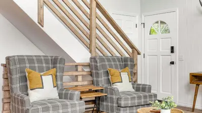 two chairs in a living room with a staircase at North Bay by AvantStay Chic Retreat w Peloton in Blue Jay