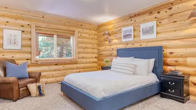 a bedroom with a blue bed and a chair at Tanglewood by AvantStay 10mins to Bear Mountain Contemporary Hillside Cabin in Big Bear Lake
