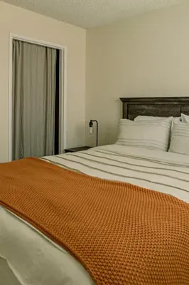 a bedroom with a large bed with an orange blanket at Cozy Family Home - 20 Mins from Disneyland in Placentia