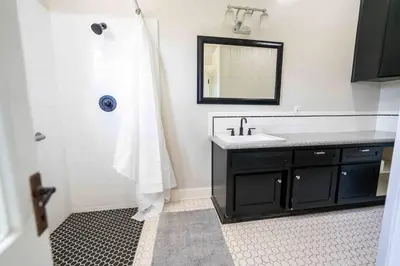 a bathroom with a sink and a shower with a mirror at Downtown 3 bed newly renovated with amenities. in Bakersfield