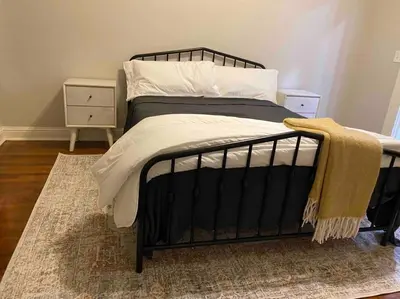 a bedroom with a black bed with a rug at Downtown 3 bed newly renovated with amenities. in Bakersfield