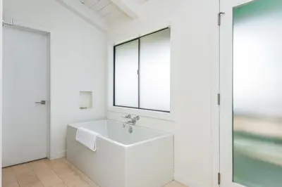 a white bathroom with a sink and a window at Luxury Modern Designer Beach House on Sand w/ Pool in Ventura