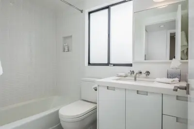 a white bathroom with a toilet and a sink at Luxury Modern Designer Beach House on Sand w/ Pool in Ventura