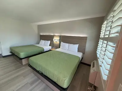 two beds in a small room with green sheets at Rosemead Motel in Rosemead