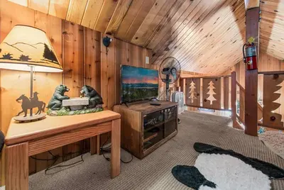 a living room with a television and a table with a lamp at Paradise Cabin in Big Bear City