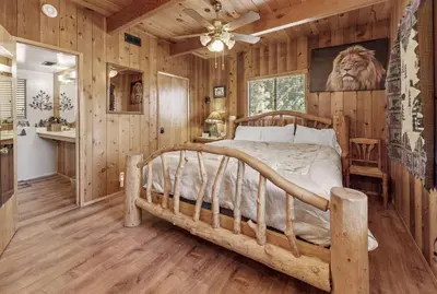 a bedroom with a bed in a room with wooden walls at Paradise Cabin in Big Bear City
