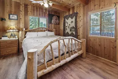a bedroom with a bed in a room with wooden walls at Paradise Cabin in Big Bear City
