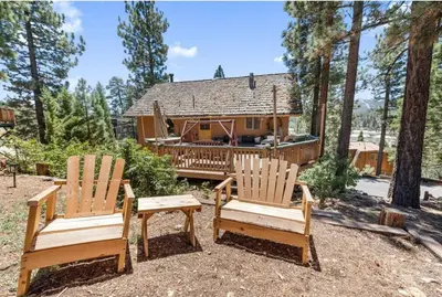 two wooden chairs sitting in front of a house at Paradise Cabin in Big Bear City