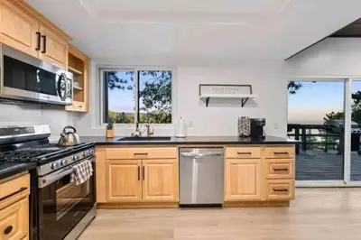 a kitchen with wooden cabinets and a view of a deck at Updated Mountain Cabin Retreat with 180 views off Deck and Balcony in Running Springs