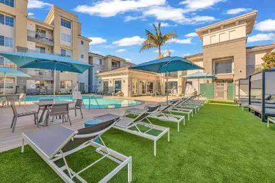 a group of lawn chairs and umbrellas next to a pool at Exclusive Suites in MDR-Venice with Pool, GYM & HotTub in Los Angeles